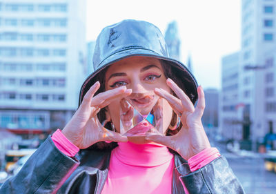 Close-up portrait of young woman holding crystal while standing in city