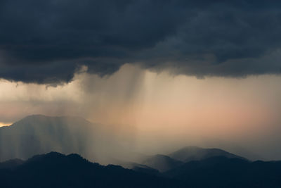 Scenic view of mountains against stormy sky