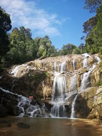 Scenic view of waterfall in forest against sky