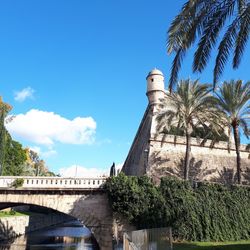 Low angle view of arch bridge by building against sky