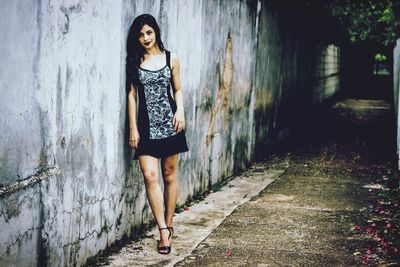 Portrait of young woman standing against wall