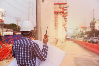 Rear view of man holding hat in city