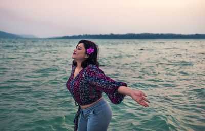 Young woman looking at sea against sky