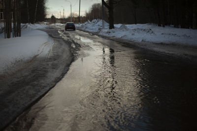 Wet road. puddle on pavement. water on highway. car left on road.