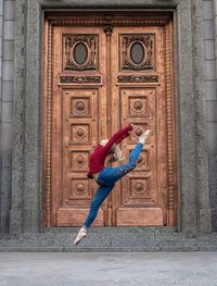 Side view of woman dancing against wall in city