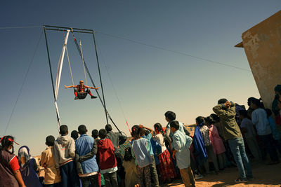 People standing in traditional windmill against clear sky during sunset