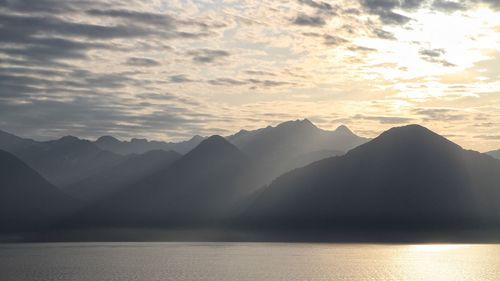 Scenic view of sea and mountains against sky during sunset