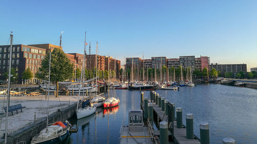Sailboats moored in harbor against buildings in city