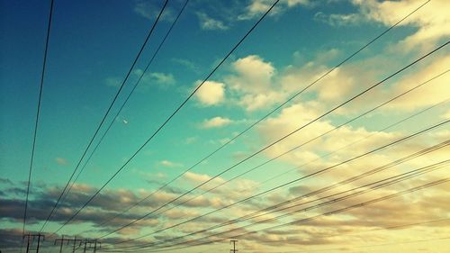 Low angle view of electricity pylon against cloudy sky