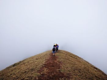 Rear view of hikers on mountain against sky