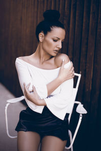 Young woman looking away while standing against wall