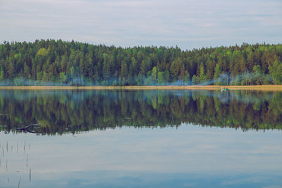 Scenic view of lake by trees against sky