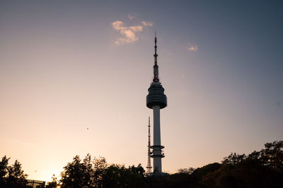 Communications tower in city against sky