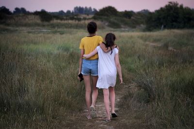 Rear view of mother and daughter on field