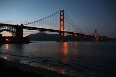 Illuminated bridge over river at night