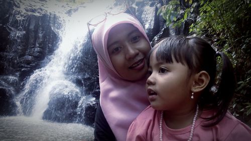 Portrait of mother and daughter against waterfall