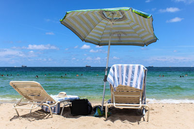 Deck chairs on beach against blue sky