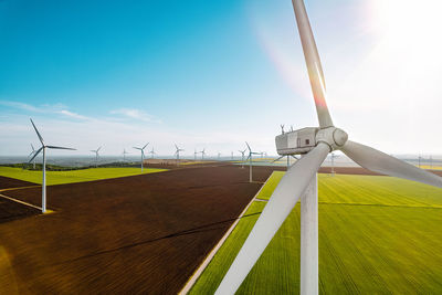 Aerial view of wind turbines farm on agricultural field in summer