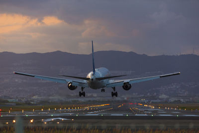 Airplane on runway against sky at sunset