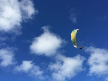 Low angle view of person paragliding against blue sky