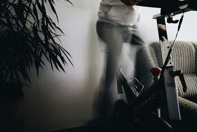 Low section of man playing piano against wall at home