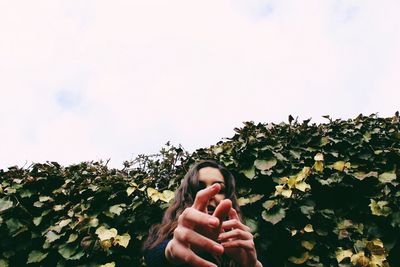 Low angle view of woman reaching against sky