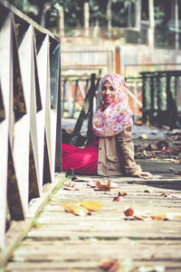 Portrait of young woman sitting on boardwalk