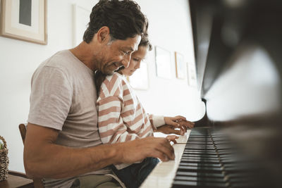 Happy father teaching piano to daughter at home