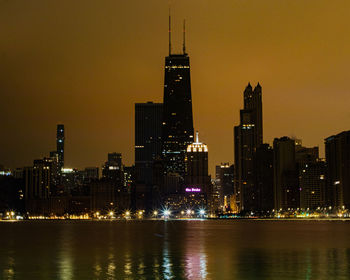 Illuminated buildings in city against sky at night