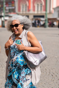 Full length of happy woman holding umbrella in city