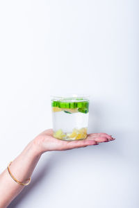 Close-up of hand holding drink against white background