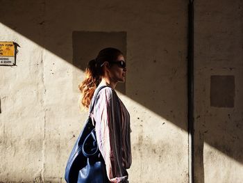 Young woman standing against wall