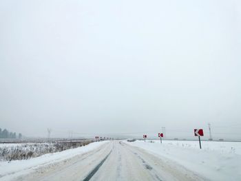 Road amidst snow covered landscape against sky