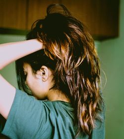 Woman with hand in hair standing at home