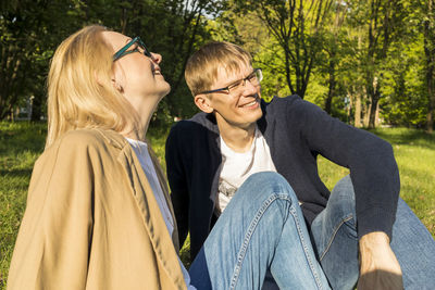 Smiling with teeth couple sits on grass in park. husband and wife enjoy time together, relationship