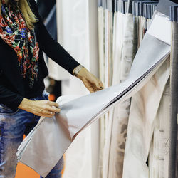 Midsection of woman holding fabric while standing in store