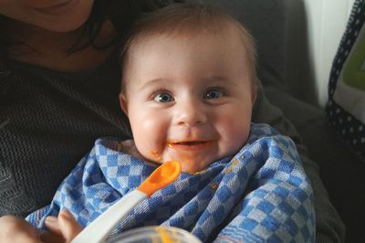 Portrait of happy baby boy fed by mother