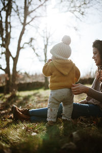 Mother and daughter wearing warm clothing on land during sunny day