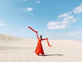 Woman with umbrella on beach against sky