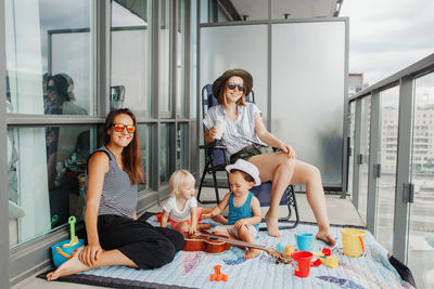 Young mothers spending time together with children babies on balcony at home. staycation 