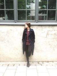 Young woman standing against window