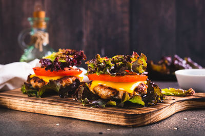 Keto burgers on lettuce leaves from cutlet, tomatoes and cheese on a board on the table