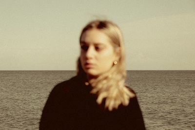 Portrait of woman standing on beach against sky