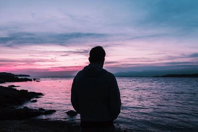 Rear view of silhouette man standing at beach during sunset