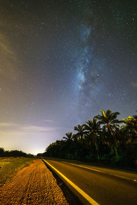 Road amidst field against sky at night