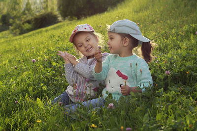 Sisters sit in nature in meadow flowers in spring at sunset