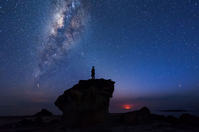 Silhouette man standing on rock formation against star field at night