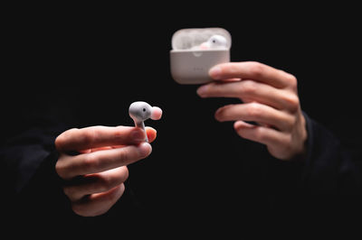 Close-up of a woman taking a white wireless earphone out of the charger. female hands touch the