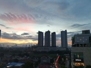 Modern buildings in city against sky during sunset