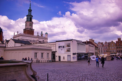 People on building in city against cloudy sky